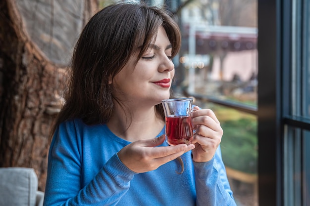 Una mujer joven en un café bebe té turco