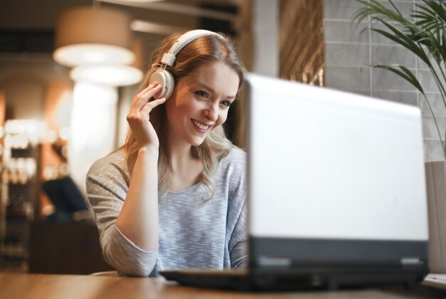 mujer joven en un café con una computadora y auriculares