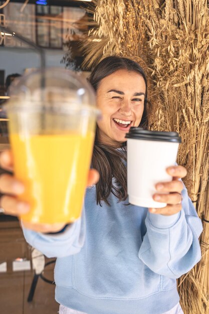 Una mujer joven en un café con una taza de café y un vaso de jugo.