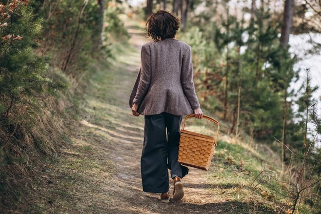 Mujer joven con caja de picnic en el bosque