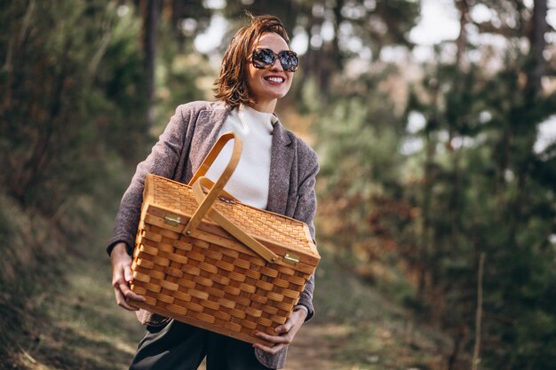 Mujer joven con caja de picnic en el bosque