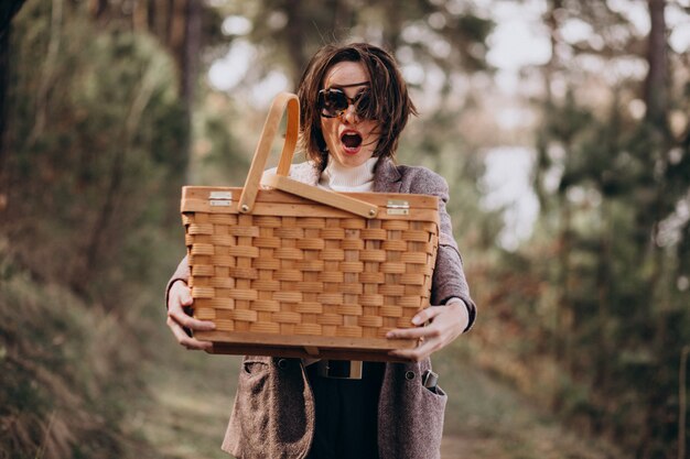 Mujer joven con caja de picnic en el bosque