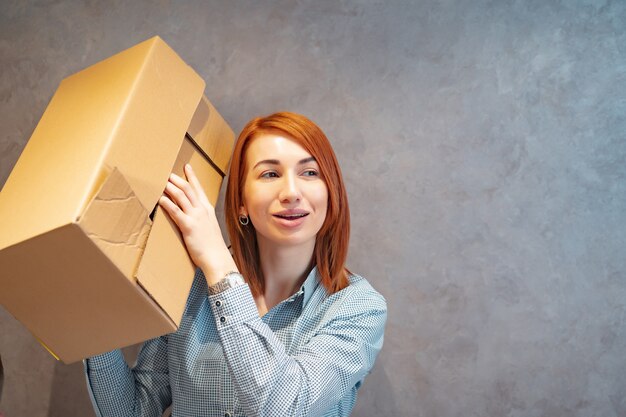 Mujer joven con cajas de cartón y lo sacude