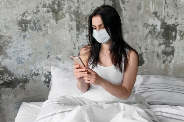 Mujer joven en la cama con mascarilla