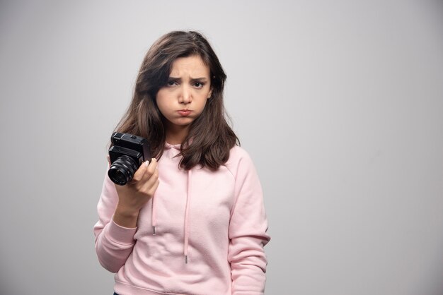 Mujer joven con cámara sintiéndose triste.