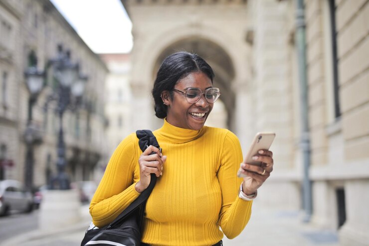 mujer joven camina por la calle con un teléfono en la mano