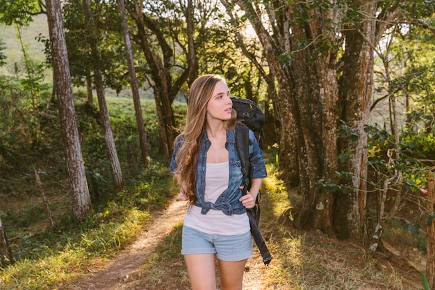 Mujer joven caminando por la pista de tierra en el bosque