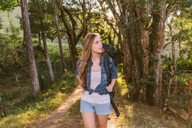 Mujer joven caminando por la pista de tierra en el bosque