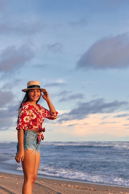 Mujer joven caminando por la playa al atardecer