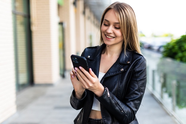 Mujer joven caminando con teléfonos inteligentes en la ciudad moderna