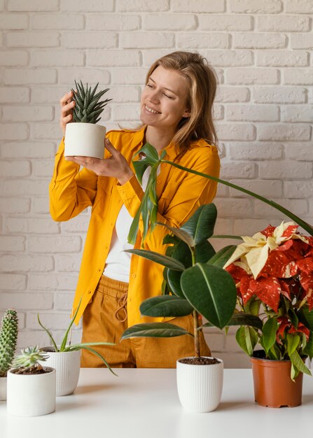 Mujer joven en camisa amarilla jardinería en casa