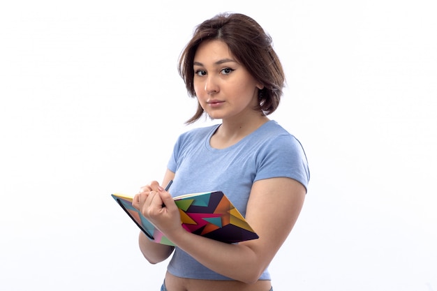 Mujer joven en camisa azul escribiendo notas