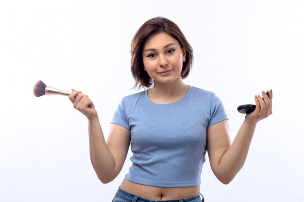 Mujer joven en camisa azul haciendo maquillaje