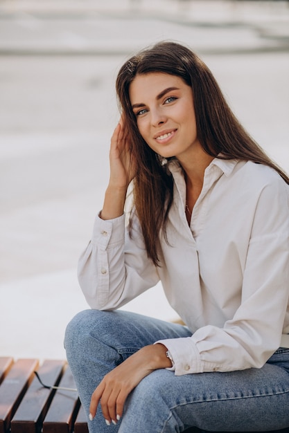 Mujer joven con camisa blanca caminando fuera de las calles de verano