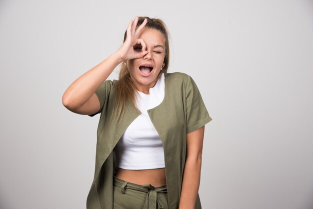 Mujer joven con camisa blanca mirando a través de su mano.