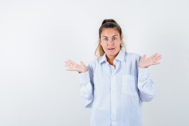 Mujer joven con camisa blanca mostrando gesto de impotencia y mirando desconcertado