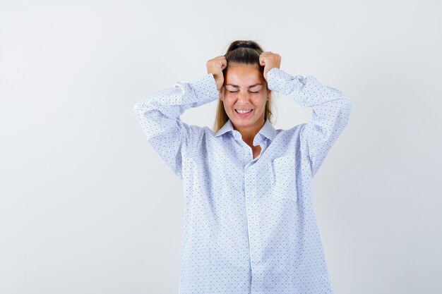 Foto gratuita mujer joven con camisa blanca poniendo las manos en las sienes y mirando feliz