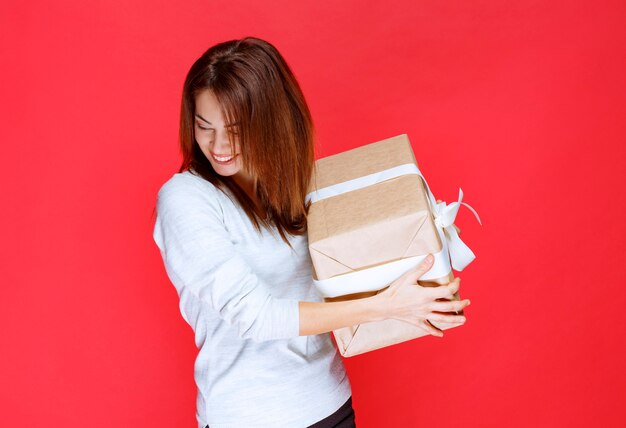 Mujer joven con camisa blanca sosteniendo una caja de regalo de cartón