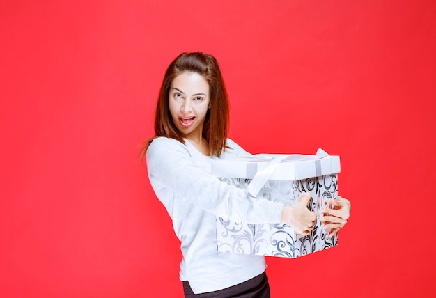 Mujer joven con camisa blanca sosteniendo una caja de regalo impresa