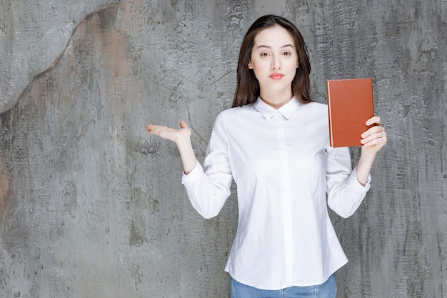 Mujer joven con camisa blanca sosteniendo un libro para su clase. foto de alta calidad
