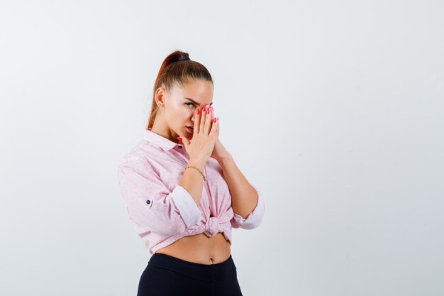 Mujer joven en camisa casual, pantalones mostrando las manos juntas en gesto de súplica