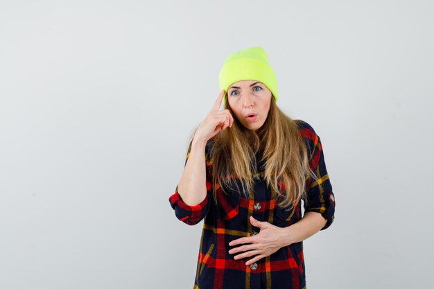 Mujer joven en una camisa a cuadros con un sombrero