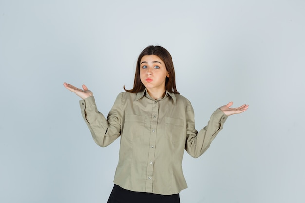 Mujer joven en camisa, falda mostrando gesto de impotencia, soplando mejillas