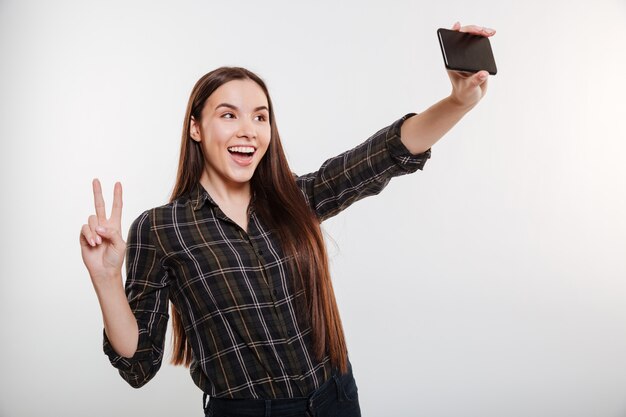 Mujer joven en camisa haciendo selfie en teléfono