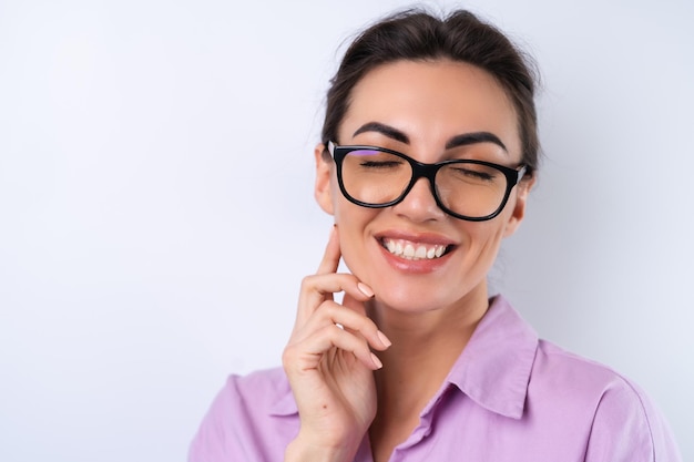 Mujer joven con una camisa lila sobre un fondo blanco con gafas para una visión alegre positiva de buen humor