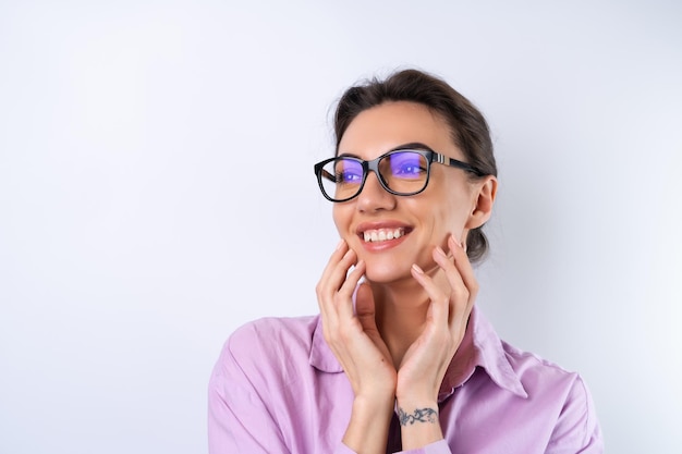 Foto gratuita mujer joven con una camisa lila sobre un fondo blanco con gafas para una visión alegre positiva de buen humor