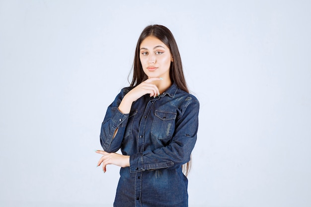 Mujer joven en camisa de mezclilla dando poses neutrales sin reacciones