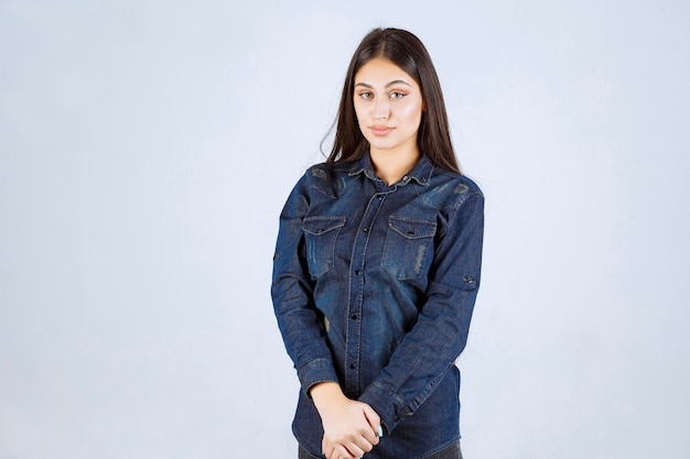 Mujer joven en camisa de mezclilla dando poses neutrales sin reacciones