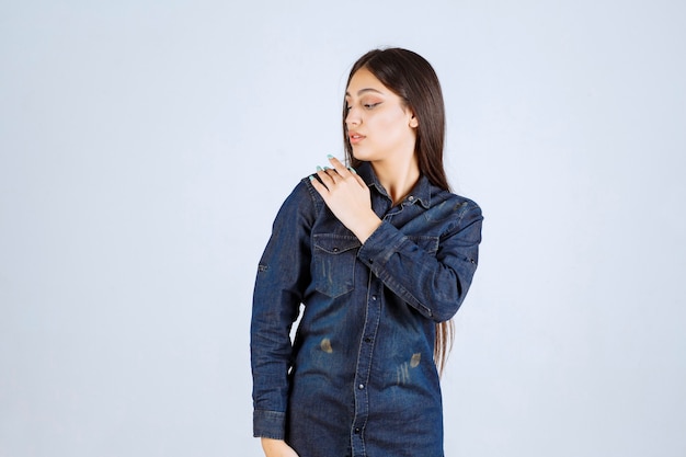 Mujer joven en camisa de mezclilla dando poses neutrales sin reacciones