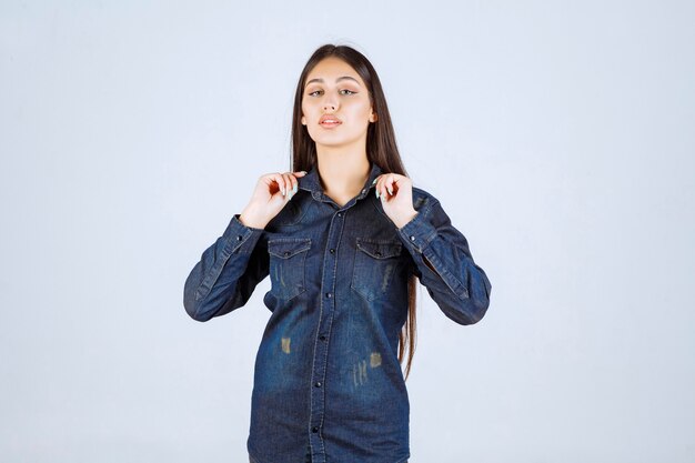 Mujer joven en camisa de mezclilla dando poses neutrales y seductoras sin reacciones