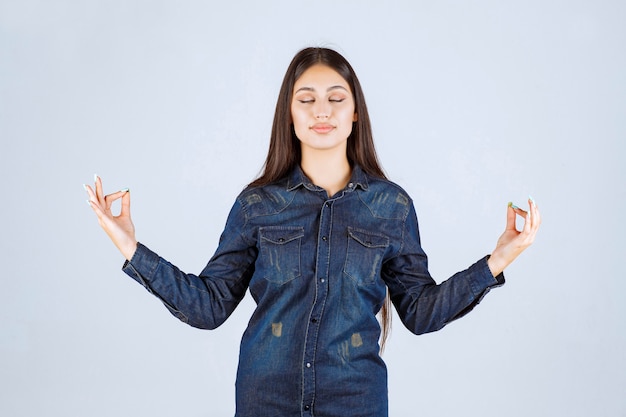 Mujer joven en camisa de mezclilla mostrando signo de disfrute