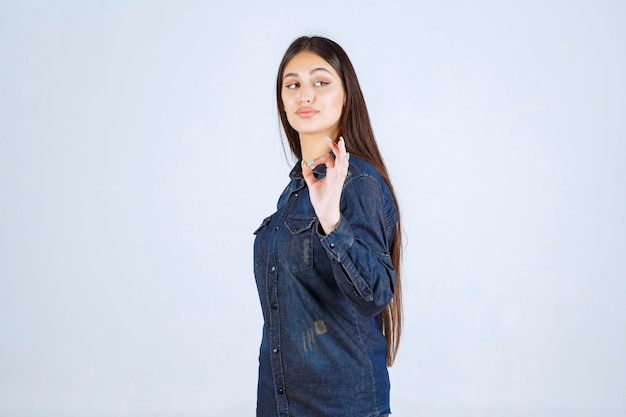 Mujer joven en camisa de mezclilla mostrando signo de disfrute