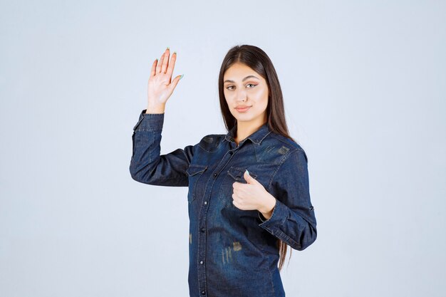 Mujer joven en camisa de mezclilla mostrando signo de mano positivo