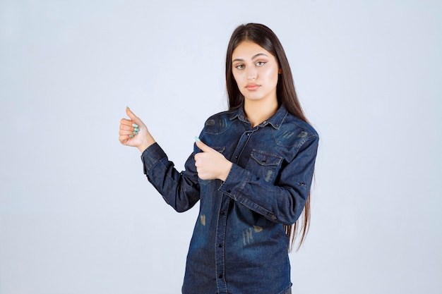 Mujer joven en camisa de mezclilla mostrando signo de mano positivo