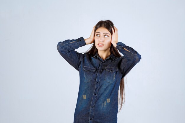 Mujer joven en camisa de mezclilla parece asustada y asustada