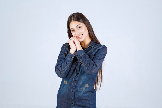 Mujer joven en camisa de mezclilla sonriendo y haciendo cara bonita