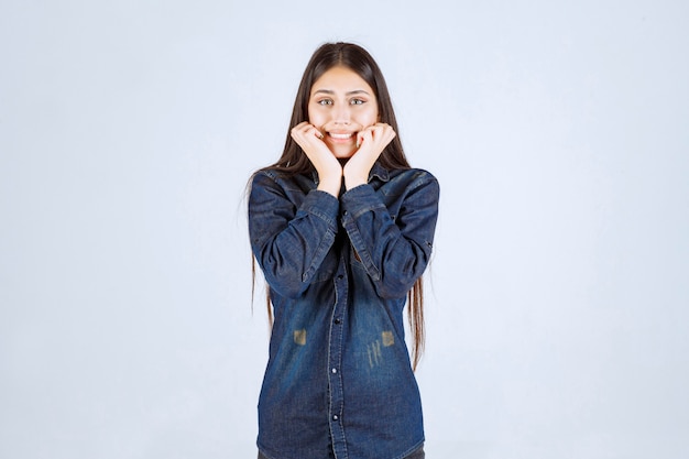 Mujer joven en camisa de mezclilla sonriendo y haciendo cara bonita