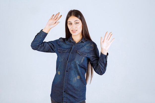 Mujer joven en camisa de mezclilla tratando de prevenir y detener algo