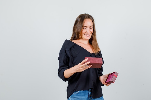 Mujer joven en camisa, pantalones cortos mirando en el cuadro actual y mirando contento