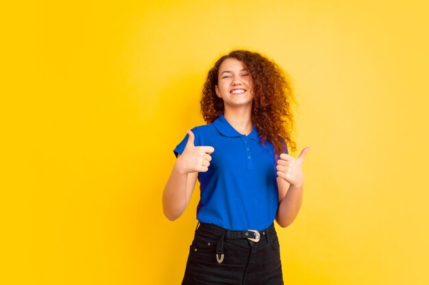 Mujer joven con camisa polo azul y pantalón azul dando pulgar hacia arriba