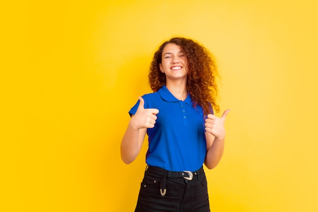 Mujer joven con camisa polo azul y pantalón azul dando pulgar hacia arriba