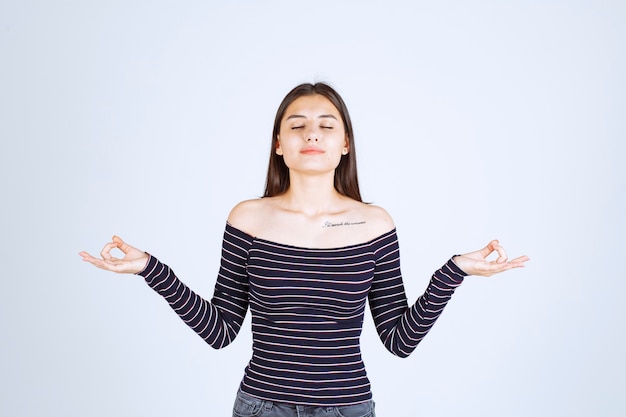 Foto gratuita mujer joven en camisa a rayas haciendo meditación