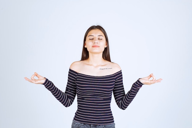 Mujer joven en camisa a rayas haciendo meditación