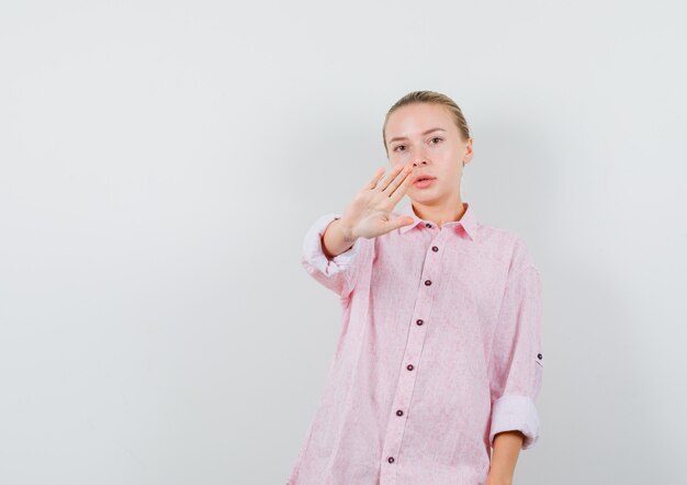 Mujer joven con camisa rosa sin gesto y mirando seria