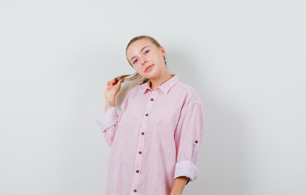 Mujer joven en camisa rosa posando mientras sostiene el hilo