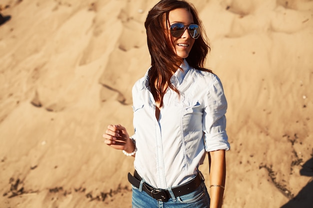 Mujer joven con camisa y vaqueros en la playa